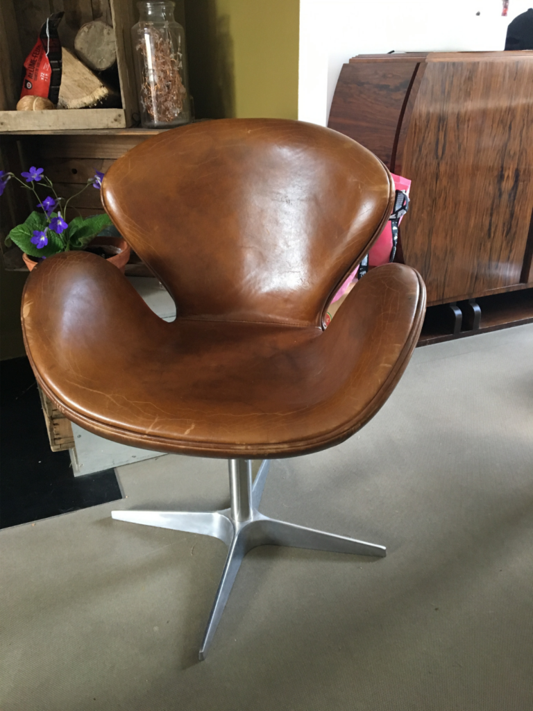 Chaise vintage en cuir marron avec base en métal exposée dans un décor intérieur.