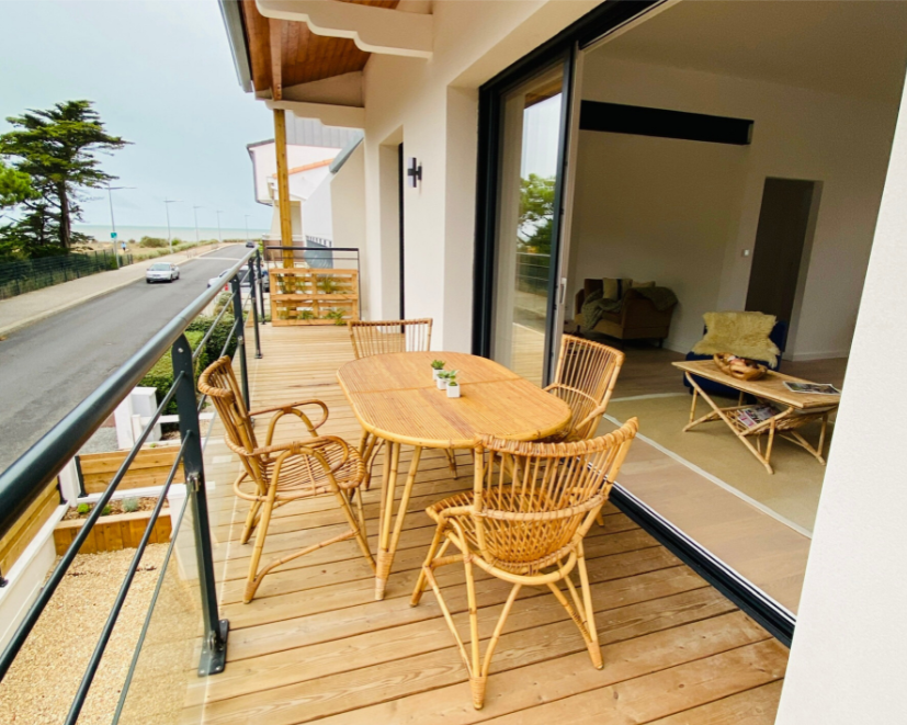 Balcon avec mobilier vintage en osier donnant sur une route.